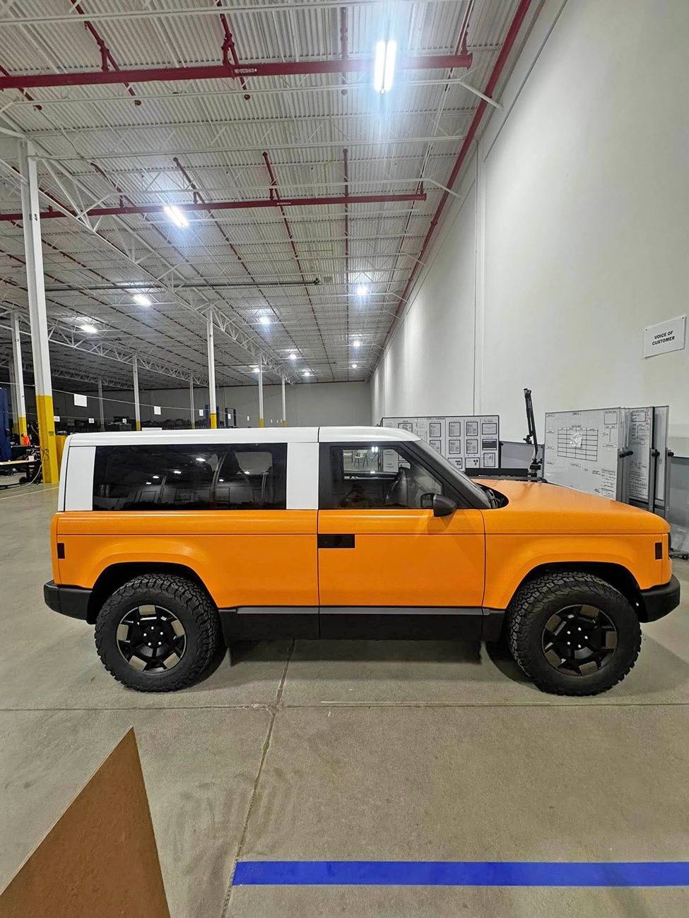 Slate Auto Pickup Truck Wrapped Orange Slate SUV and Pickup (with white roofs) inside Slate's pre-production facility Wrapped Slate SUV white roof 3